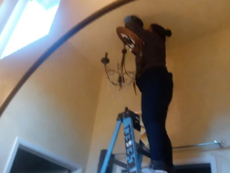 Electrician installing a chandelier in a Johnson residence